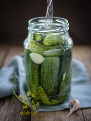 Pickling cucumbers .  Gucumbers , glass jar , garlic ,dill, currant leaves on a wooden table. Russian Traditional food .  pickled cucumbers . Recipes .