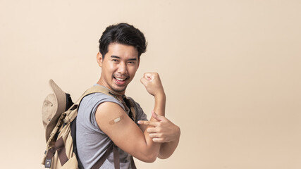Portrait Asian man backpacker happy smile and finger pointing to bandage on arm after getting a...