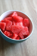 Bowl of watermelon cubes on wooden table. Selective focus.