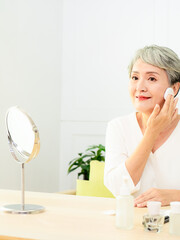 Portrait of beautiful senior asian woman applying powder puff at cheek makeup of cosmetic.