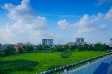 Fototapeta na wymiar Kolkata cityscape , old and modern architecture of buildings, blue sky and white clouds in background with green field foreground.