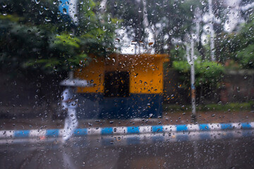 Image shot through raindrops falling on wet glass, abstract blur of city - monsoon stock image of Kolkata (formerly Calcutta) city ,