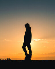silhouette of an tourist man at sunset with orange sky in the top view of mountain
