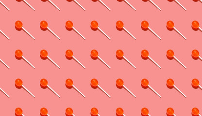 Seamless pattern of ball lollipops on stick above a pink background. Festive background for holiday paper.