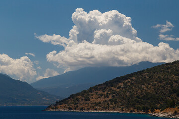 Fototapeta na wymiar A fantastic view at Cephalonia island, famous and extremely popular travel destination in Greece, Europe. Blue Ionian sea water, hills and beautiful cumulus clouds.
