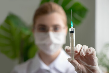 Doctor or scientist in lab hospital with injection syringe in hand. Close up, selective focus