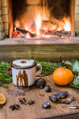 White enameled mug with hot chocolate before cozy fireplace.