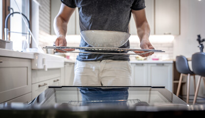 A man in front of an open dishwasher with a plate.