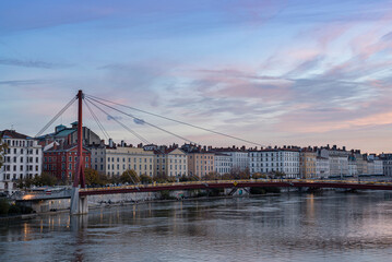 Rhone river banks with a metal pedestrian bridge on the background at old Lyon city during sunset.
