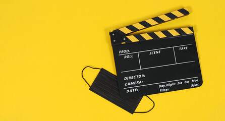 Fototapeta na wymiar Clapperboard or movie slate and black face mask on yellow background. Yellow and black color.