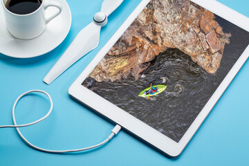 paddling a whitewater inflatable kayak on a mountain river in early spring - Poudre River in northern Colorado, reviewing aerial image on a digital tablet with coffee