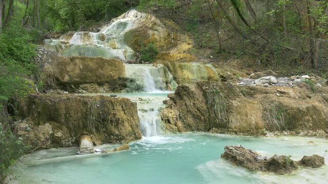 Geothermal pool and hot spring in Tuscany, Italy. Bagni San Filippo natural thermal waterfall in the morning with no people. The White Whale amidst forest.