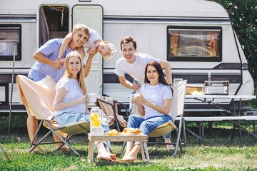 Friends, two women, two men and a child, beautiful and happy, relax together, traveling in a trailer, a mobile home
