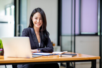 Portrait of Happy Young attractive business woman using digital laptop computer. do math finance on wooden desk, tax, accounting, report statistics and analytical research technology concept.