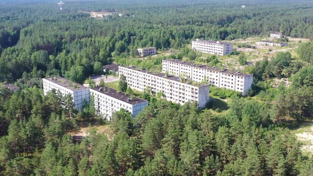 Aerial view orbiting around abandoned soviet military town Irbene in Latvia. Radio telescope in background