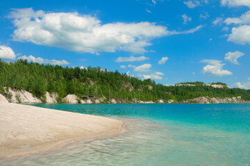 Sandy beach near the lake against the background of the forest and blue sky, relax