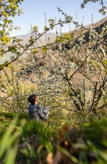 Portrait of an attractive young female surrounded by cherry trees during the blossom season at the end of March