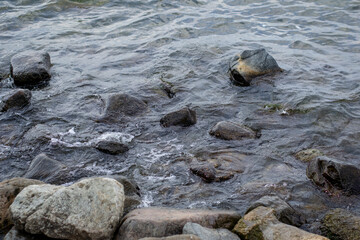 Lake water waves hitting shore rocks