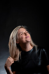 Attractive blonde cute girl grimaces on a dark background in the studio.