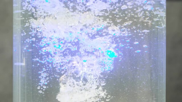 Close up of working device for enriching water with oxygen. HDR. Moving air bubbles in a transparent vessel.