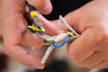 Young man hands peeling a wire using a plier to repair it.