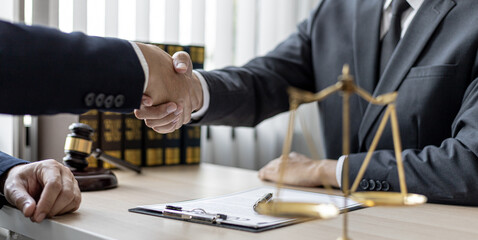 Lawyer and client shake hands, sign a lawsuit for the client, in which the client has filed a lawsuit against an employee of a company that commits fraud. The concept of litigation counseling.