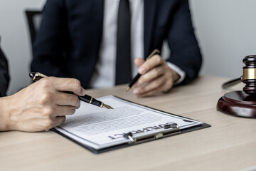 Two male lawyers are consulting together to draft a contract acknowledgment for their clients, they...