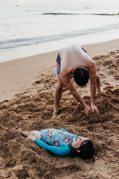 Father hurries daughter in the sand on a beach on Oahu, Hawaii