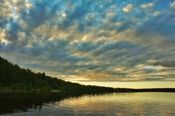 Ragged clouds over a forest lake at sunset

