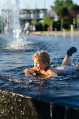Fototapeta premium boy 2 years old bathes in a fountain, free space