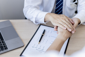 The doctor shakes hands to encourage the patient after the diagnosis results are finished, the patient detected a serious disease in the early stages. Concept of disease diagnosis.