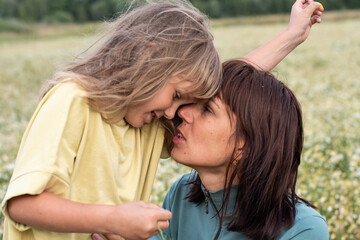 portrait of a mother and daughter in a summer field. a woman and a girl collect daisies in a chamomile field. children and parents