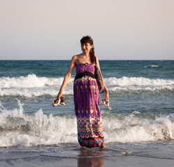 woman in a summer dress stands in the sea