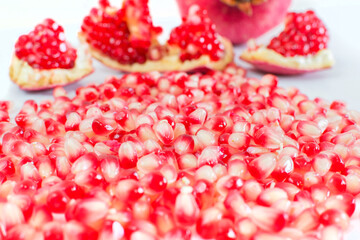 part of a pomegranate fruit with pomegranate seeds on white background