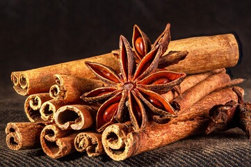 Christmas baking spices, cinnamon sticks and anise stars for Christmas cake, cookies or mulled wine on a black background, macro photo