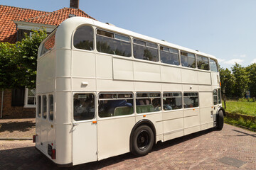 White high double decker bus rides over the narrow dike through the picturesque village of Amerongen