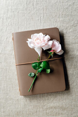A garden rose lies on a notepad.