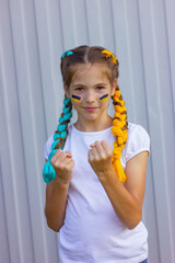 cheerful Ukrainian girl with blue and yellow hair shows her strength. sport and fan support concept. patriotism and independence of Ukraine.