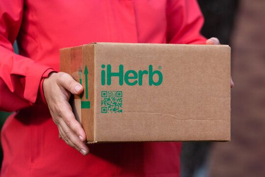 Person with iHerb parcel in hands. Close up of midsection.