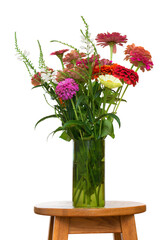 Bouquet of color zinnia flowers in a glass vase on white background