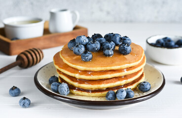 Homemade pancakes on a white plate with honey and blueberries for breakfast. Good morning!