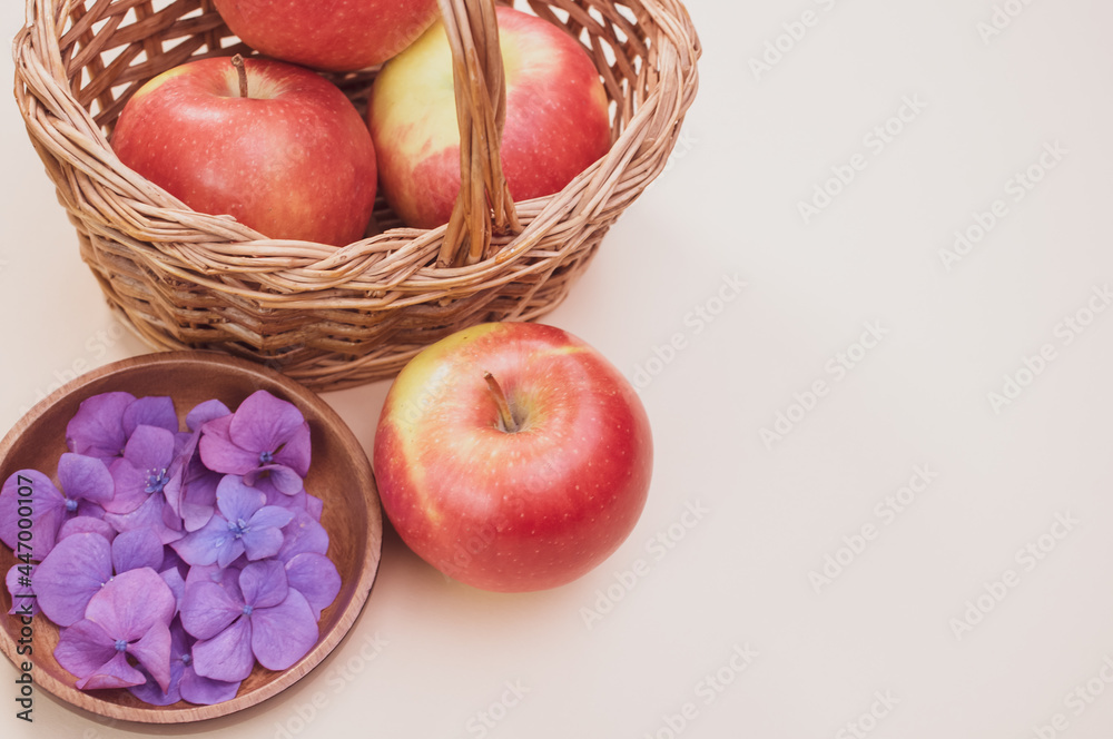 Sticker Wicker basket of red apples and hydrangea petals isolated on a cream background