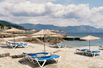 Fototapeta na wymiar Cobbled beach with sun loungers and parasols near the sea