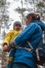Happy family Mom and child walk in the forest after rain in raincoats together, hug and look at each other