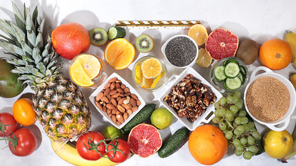 Assorted fresh summer tropical fruits, vegetables and nuts on bright sunny table, citrus mix, detox diet and weight loss concept, banner, store advertisement, healthy and natural food,
