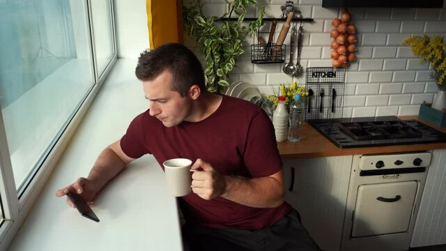 a man drinking tea and watching a video on his phone