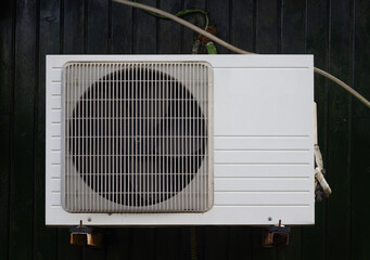 White air conditioner compressor unit outside the house with green wooden background. Selective...