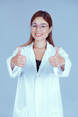 Doctor woman  giving a thumbs up gesture and smiling because something good has happened on blue background