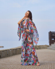 Young beautiful and elegant woman with long brunette hair wearing summer dress with floral design...