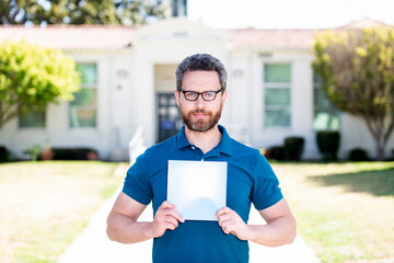 teacher man in glasses showing paper sheet, back to school